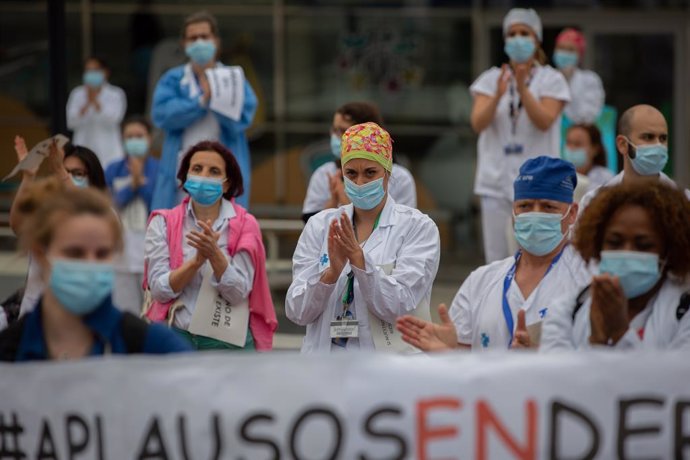 Desenes de membres del personal sanitari protegits amb mascarilla sostenen cartells durant la concentració de sanitaris en el Dia Internacional de la Infermeria a les portes de l'Hospital Vall d'Hebron, a Barcelona, a 12 de maig de 2020.