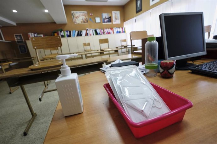 Mascarillas y gel desinfectante en la mesa del profesor de un aula donde se pueden observar los pupitres colocados y separados entre sí para el nuevo curso del colegio Virgen de Europa, debido a las nuevas medidas de distanciamiento que se han de tomar 