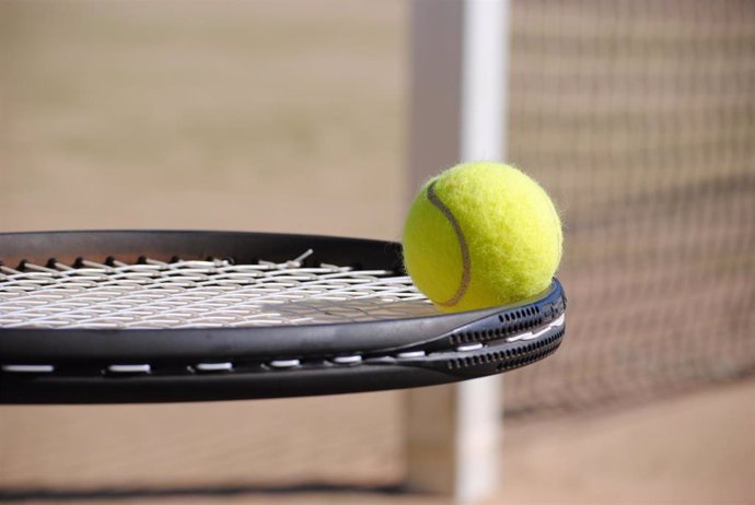 Una raqueta de tenis sostiene una pelota, foto de archivo
