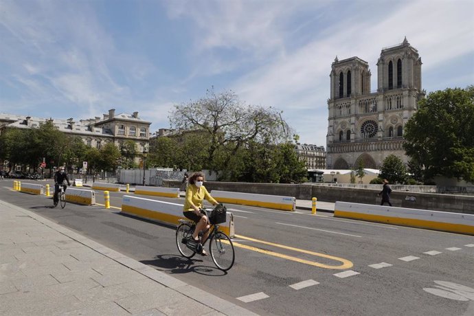 Una mujer en bicicleta y con mascarilla en París