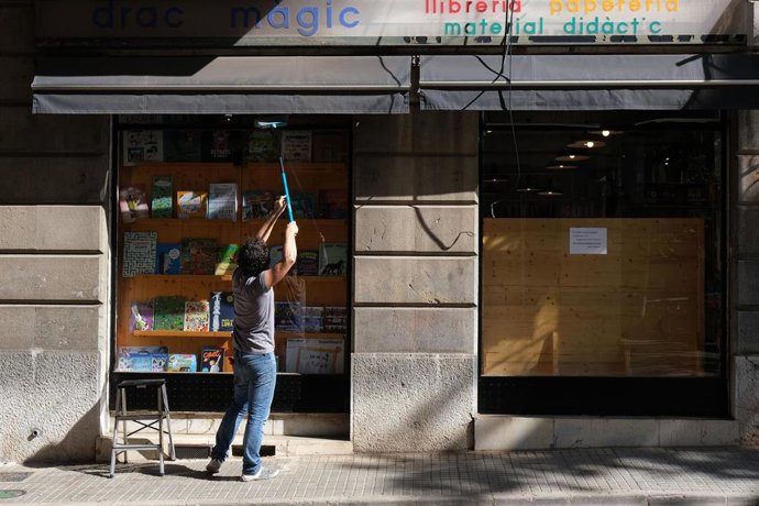 Una persona sube el cierre de una librería en Palma en la fase 1.