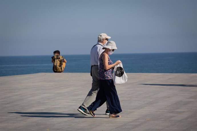Dos personas protegidas con mascarillas pasean por el Paseo Marítimo de la Playa de la Barceloneta durante el día 66 del estado de alarma decretado por el Gobierno a causa del Covid-19, en Barcelona/Catalunya (España) a 20 de mayo de 2020.