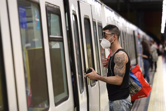 Un pasajero abre la puerta de un tren de Metro de Madrid.