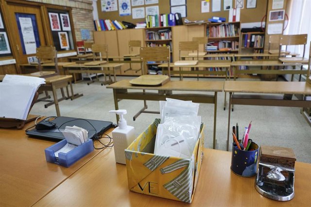 Mascarillas y gel desinfectante en la mesa del profesor de un aula  de un colegio