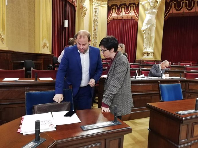 El conseller Miquel Mir conversa con la portavoz socialista, Sílvia Cano, en el Parlament.
