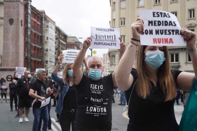 Un hombre y una mujer sostienen carteles durante la manifestación en Bilbao con la participación de hosteleros vizcaínos 