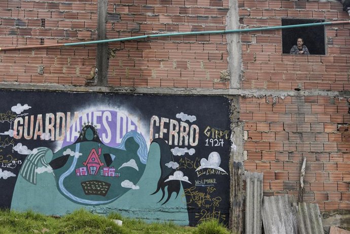 Una mujer mira desde la ventana durante el confinamiento por la pandemia de coronavirus en El Codito, un suburbio de Bogotá