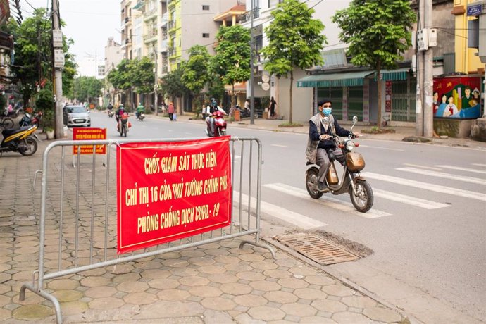 Un hombre con mascarilla circula en moto por las calles de Hanói