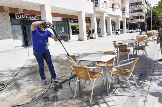 Un trabajador de un restaurante desinfecta las sillas de su terraza. 