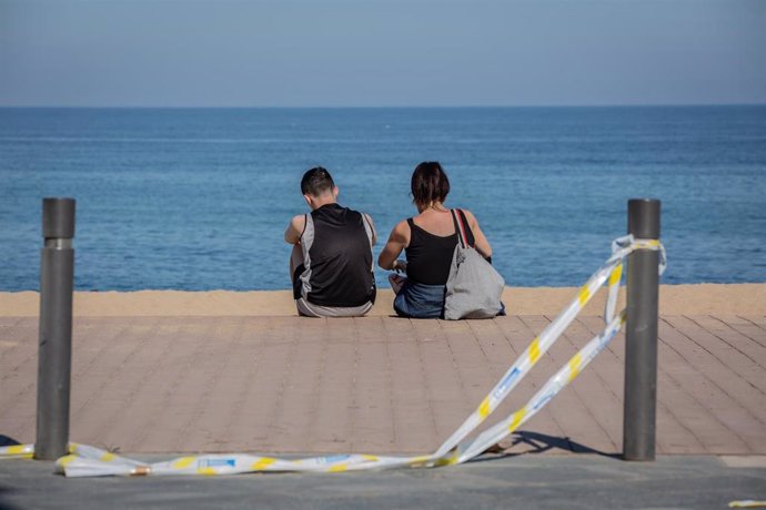 Dos jóvenes sentados en el Paseo Marítimo de la Playa de la Barceloneta, en Barcelona/Catalunya (España) a 20 de mayo de 2020.