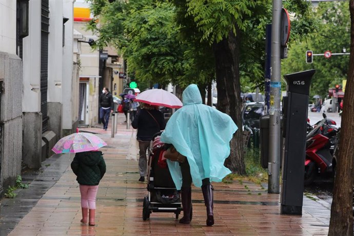 Una mujer y una niña pasean con paraguas en Madrid en un día de lluvia y bajada de temperaturas