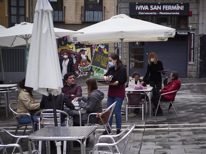 Una camarera atiende a varias personas sentadas en una terraza de Navarra donde los empleados utilizan un metro para asegurarse de que las medidas de distanciamiento son las correctas entre los potenciales clientes de la terraza de un bar en el centro d