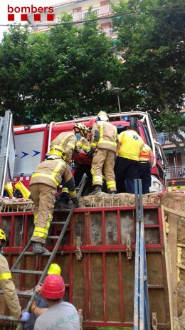 Efectivos de Bomberos de la Generalitat rescatan a un trabajador atrapado tras volcar una carretilla elevadora en Molins de Rei (Barcelona).