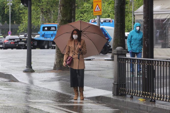 Una mujer con paraguas en Madrid en un día de lluvia y bajada de temperaturas en toda España, en que en gran parte de la Península y Baleares se espera nubosidad, con chubascos y tormentas casi generalizados, que podrán ser localmente fuertes o persiste