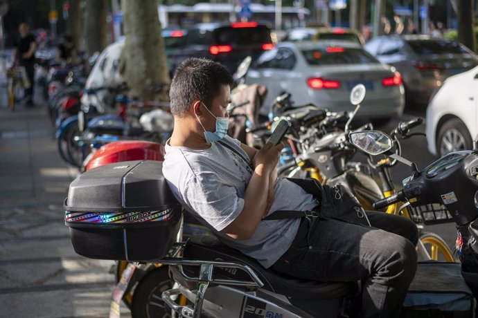 Un repartidor de comida a domicilio descansa sobre su motocicleta en Shanghái.