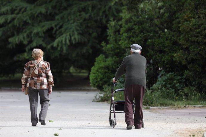 Una mujer y un hombre de edad avanzada con andador paseando.