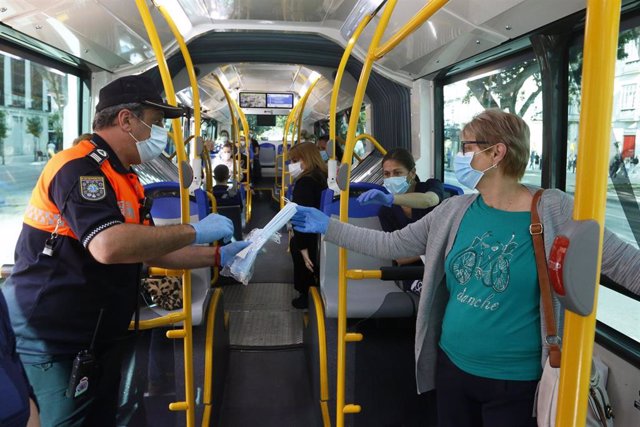Miembros de protección civil de Málaga entregan mascarillas a los pasajeros de autobuses, durante la fase 0 de la desescalada del Gobierno en el inicio de la semana 8 del estado de alarma decretado por el coronavirus y en el día en el que entra en vigor l