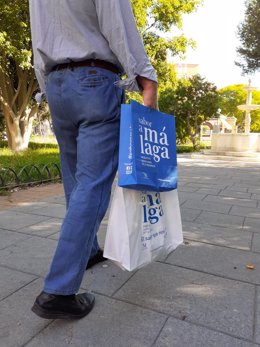 Una persona camina con bolsas de Sabor a Málaga, que engloba a productores de la provincia de Malaga