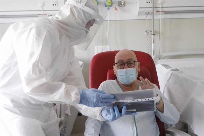 Un trabajador sanitario ayuda a hacer una videoconferencia en la habitación de un paciente negativo de Covid-19 en el Hospital Arnau de Vilanova, en Valencia, Comunidad Valenciana, (España), a 24 de abril de 2020.