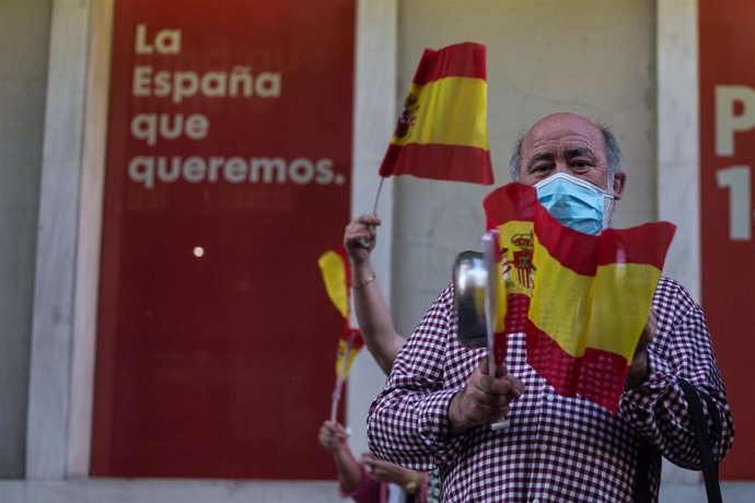 Un hombre mayor golpea una cacerola en señal de protesta, en la sede del PSOE.