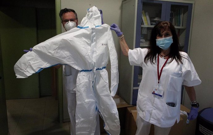Dos sanitarios del Centro de Salud García Noblejas muestran uno de los trajes de protección frente al Covid-19 