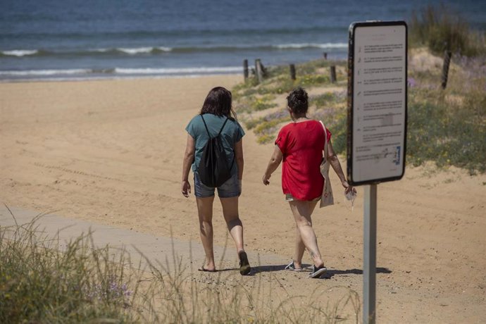 Dos personas caminan hacia la playa de Punta Umbría, (Huelva) abierta para el paseo y la práctica deportiva como único uso permitido, durante la segunda semana de la fase 1 de la desescalada.