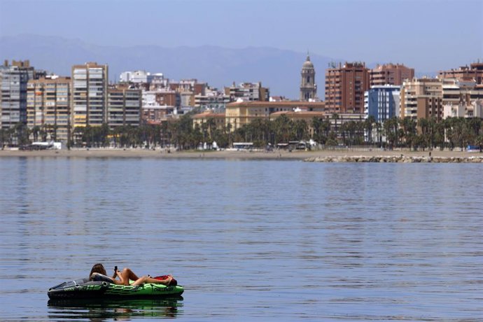 Una mujer toma el sol sobre un kayac en la playa de La Caleta durante la Fase 1 en Málaga a 20 de mayo del 2020
