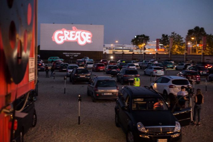 Varias personas ven la película de Grease desde el aparcamiento durante la apertura del Auto-Cine RACE con las medidas de seguridad 
