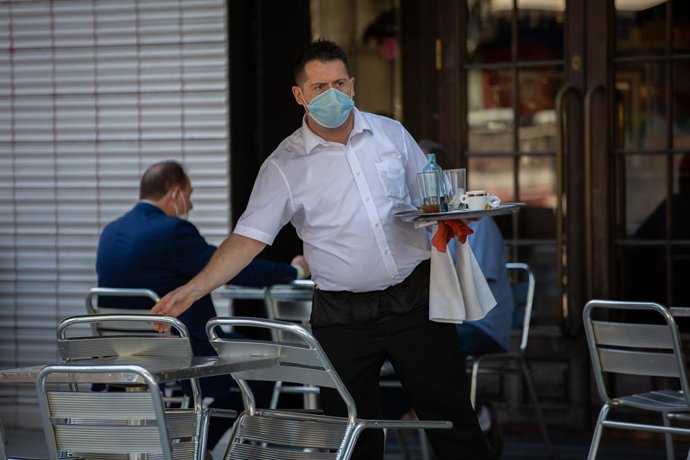 Un cambrer serveix a la terrassa d'un bar de Barcelona