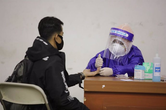 Un trabajador sanitario toma una muestra para una prueba de coronavirus en la localidad indonesia de Bandung