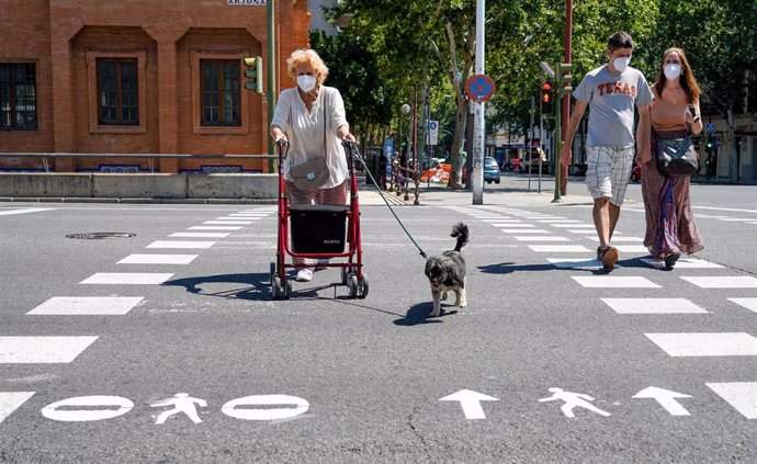 Ciudadanos  pasando por las señales pintadas en los pasos de peatones para cruzar con seguridad en el  primer día del uso obligatorio de mascarillas por el Covid-19. Sevilla a 21 de mayo del 2020