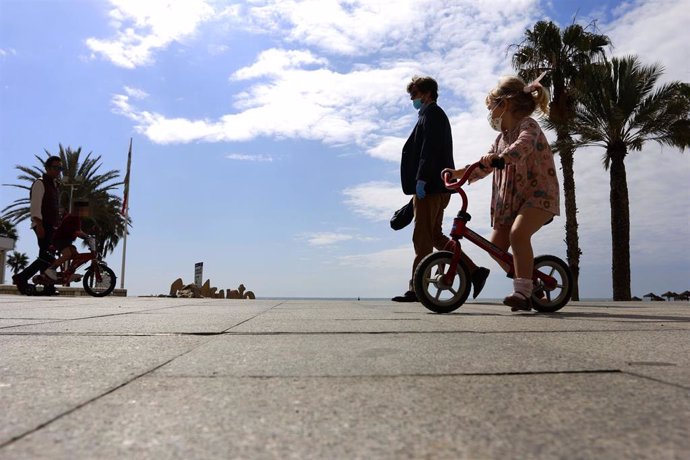 Una mujer y una niña protegidas con mascarilla por el paseo de La Malagueta el primer día en el que los menores de 14 años pueden salir, en Málaga (Andalucía ,España) a 26 de abril de 2020.