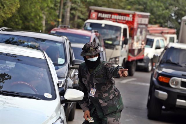 Un policía da indicaciones a un conductor en un puesto de control en Manila