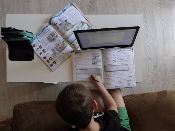 Un alumno de primaria hace los deberes de la asignatura de Inglés con varios libros y un ordenador en su domicilio de Madrid.