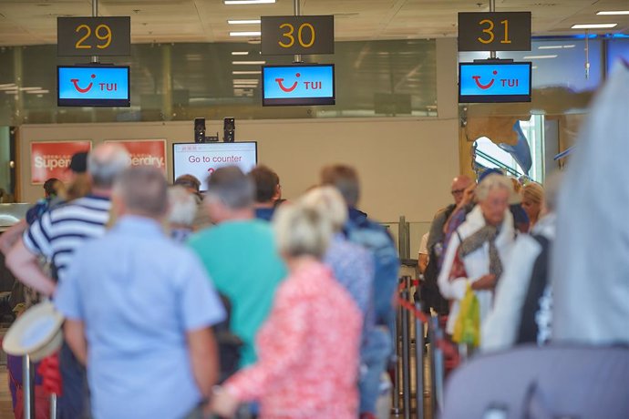 Varios turistas en el aeropuerto hacen cola en el mostrador de la compañía aérea TUI.