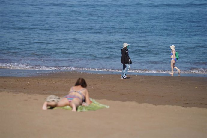 Varias personas pasean y toman el sol en la Playa de Ereaga en Getxo