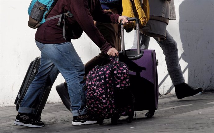 Un grupo de turistas caminan con sus maletas por una calle de Madrid.