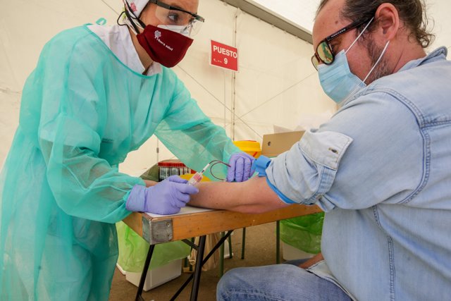 Una trabajadora sanitaria totalmente protegida, realiza una prueba diagnóstica del coronavirus a uno de los vecinos del municipio madrileño de Torrejón