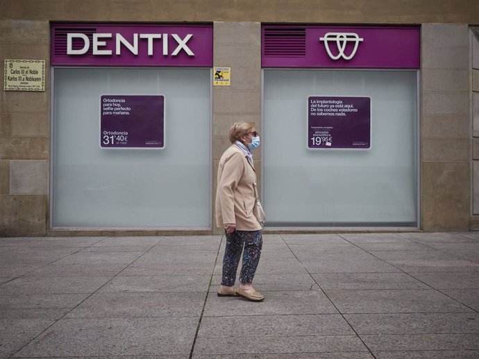 Una mujer paseas enfrente de una clínica Dentix el día en el que está permitida la apertura de locales y establecimientos minoristas con independencia de su superficie útil de exposición y venta. En Pamplona, Navarra (España), a 25 de mayo de 2020.