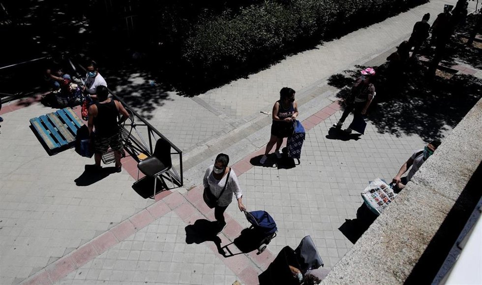 Colas de personas esperan a las puertas de la Parroquia Santa María Micaela de Madrid para recibir alimentos.