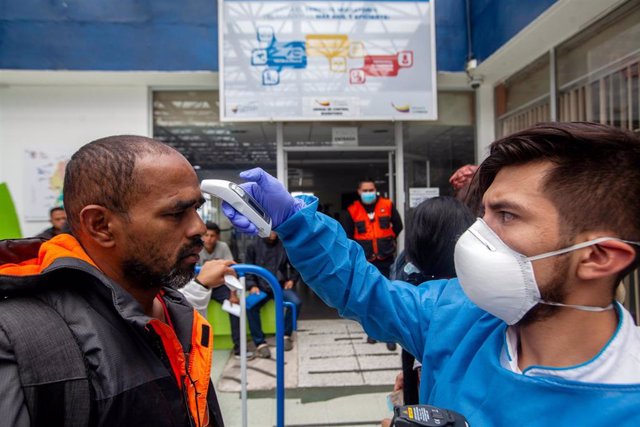 Médico ecuatoriano toma  la temperatura a un hombre en la frontera con Colombia.