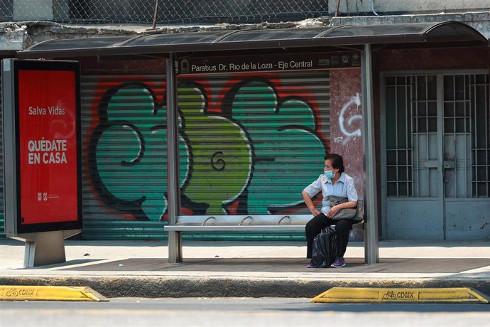 Una mujer con mascarilla espera en una parada de autobús en Ciudad de México.