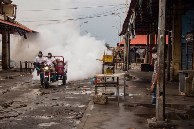 Dos hombres desinfectan el Mercado Las Pulgas, foco de infección de coronavirus en Maracaibo, Venezuela. 