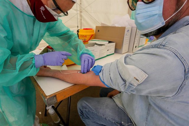 Una trabajadora sanitaria totalmente protegida, realiza una prueba diagnóstica del coronavirus a uno de los vecinos del municipio madrileño de Torrejón de Ardoz.