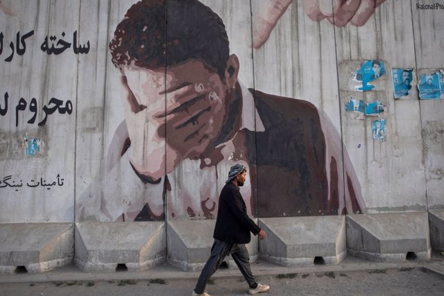 Un ciudadano pasea ante un mural por Kabul