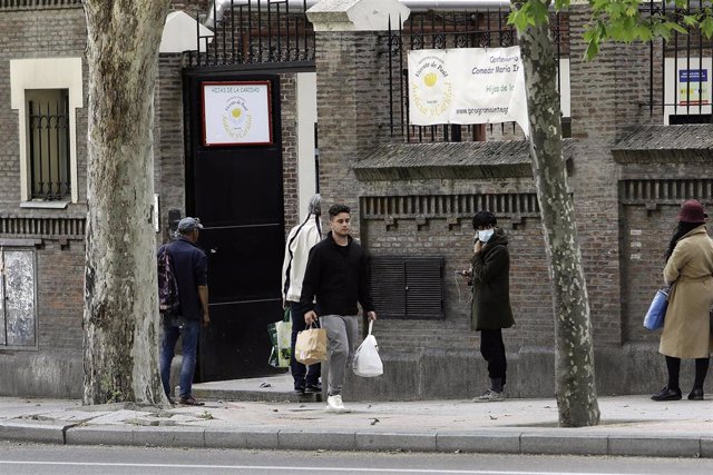 Decenas de personas esperan en la cola a las puertas del Comedor Social María Inmaculada de la capital para recoger alimentos y productos de primera necesidad en plena pandemia del Covid-19, durante el primer día en que los españoles pueden salir de casa 