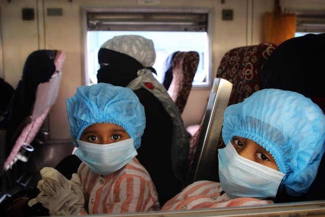 Niños con mascarillas y gorros en un tren en Daca (Bangladesh)