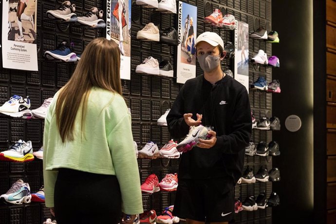 Dependiente de tienda Nike con mascarilla en la reapertura de tiendas tras la crisis del coronavirus