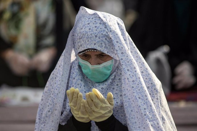 Una mujer reza con guantes y mascarilla en Teherábn