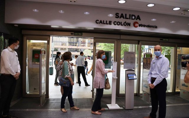 Una clienta se desinfecta las manos a la entrada de un comercio en Valencia respetando la distancia de seguridad en el primer día de la Fase 2 de desescalada, cuando se reanuda su actividad y se reabren los centros comerciales mayores de 400 metros